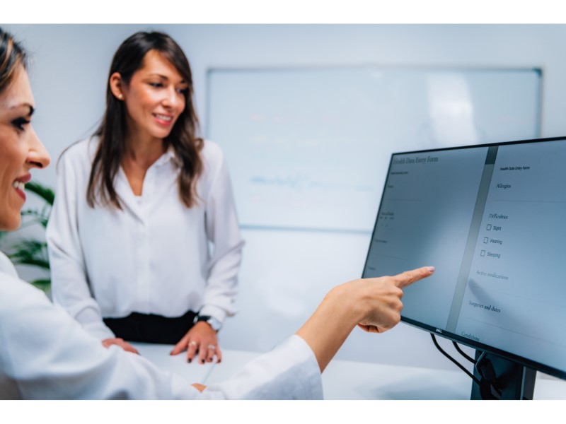 A woman using a computer to teach another woman beside her